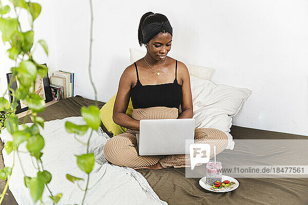 Smiling pregnant freelancer using laptop at home