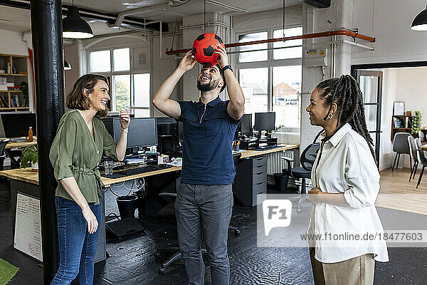 Happy business people playing with ball in office
