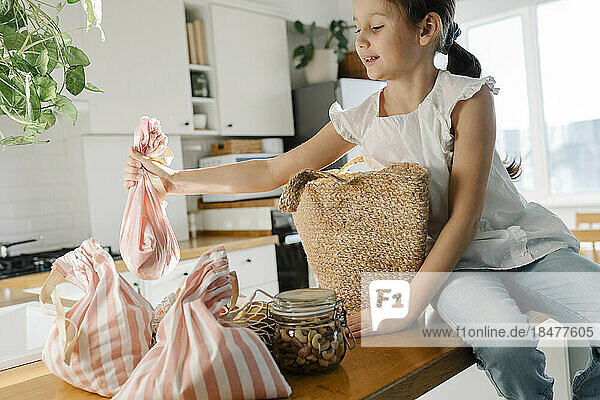 Girl with reusable bags sitting on kitchen island