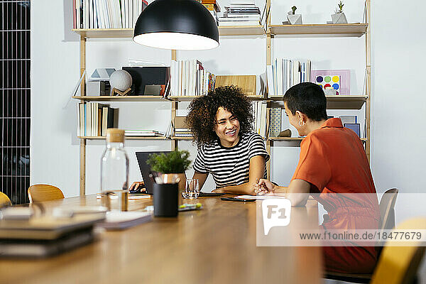 Smiling businesswoman with coworker sitting at table
