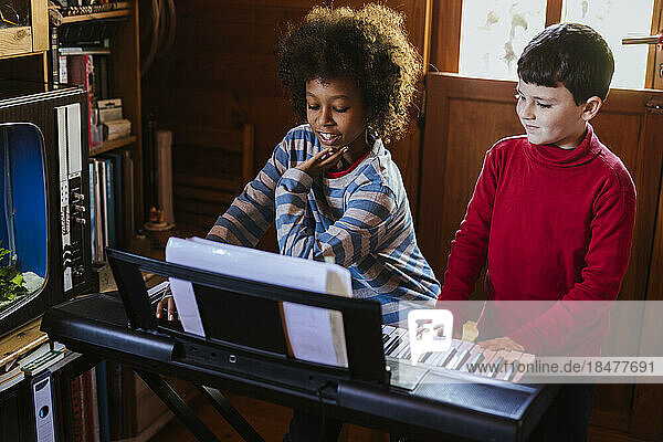 Junge spielt zu Hause von einem Freund E-Piano