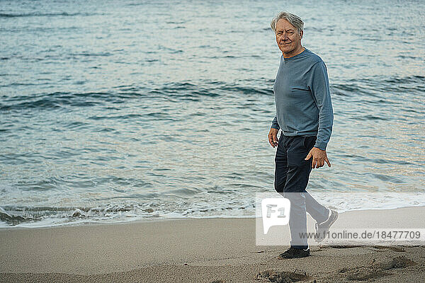 Smiling senior man walking on beach