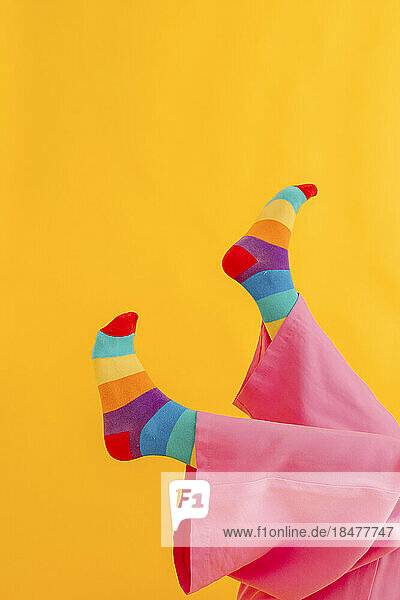 Feet of woman with rainbow color socks over yellow background