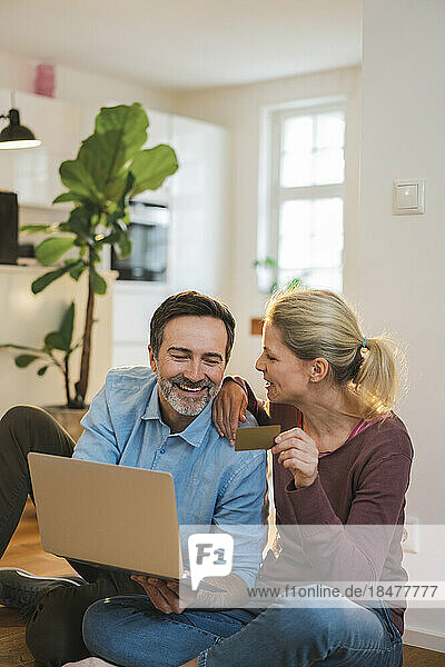 Happy couple enjoying doing online shopping at home