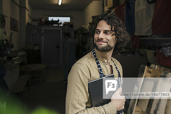 Smiling young businessman holding tablet computer in storage room