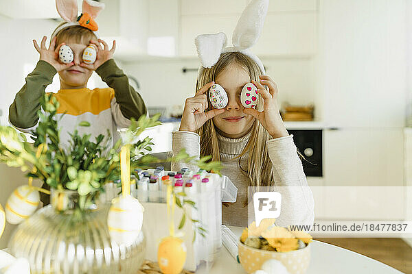 Happy boy and girl holding Easter eggs over eyes