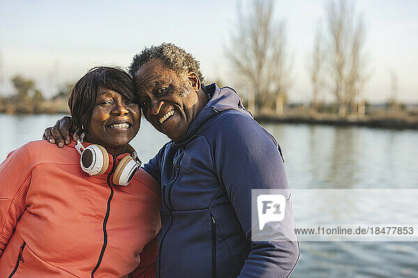 Happy senior couple in front of lake at sunset