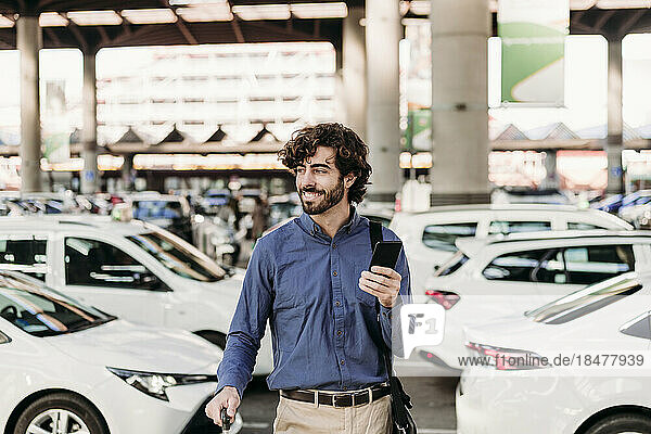 Happy businessman standing in front of cars on road