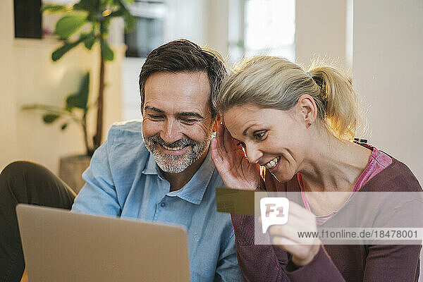 Happy couple doing online shopping through laptop at home