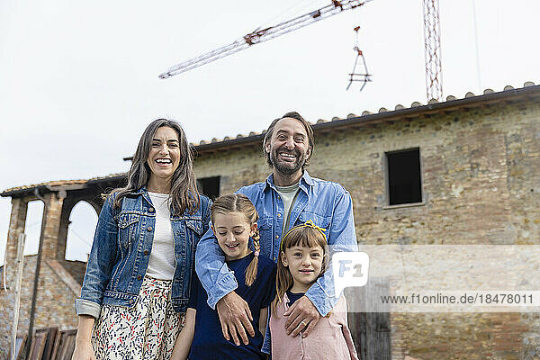 Cheerful family standing together in front of house