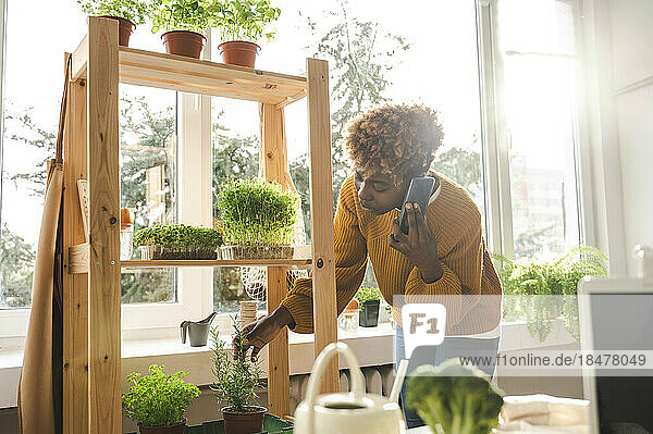 Woman talking on smart phone with plants on shelf