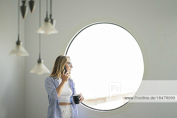 Businesswoman talking on smart phone looking out of window