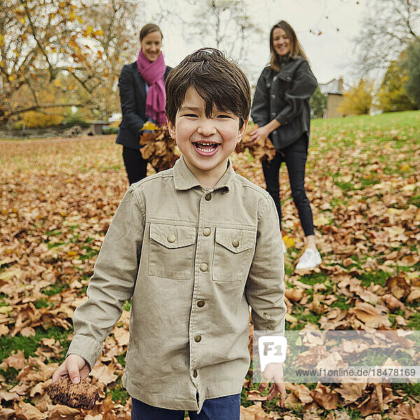 Happy boy standing on autumn leaves at park