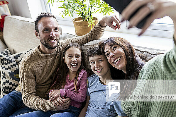 Glückliche Frau  die zu Hause ein Selfie mit der Familie auf dem Sofa macht