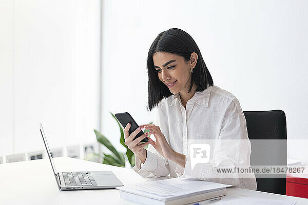 Smiling businesswoman using mobile phone at desk
