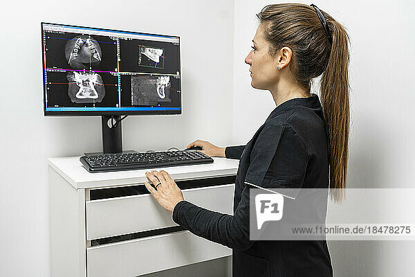 Female doctor examining x-ray image on computer at clinic