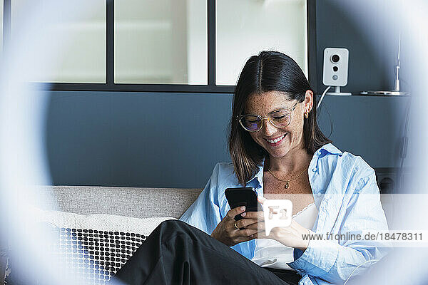 Glückliche Frau  die zu Hause Textnachrichten auf dem Smartphone sendet