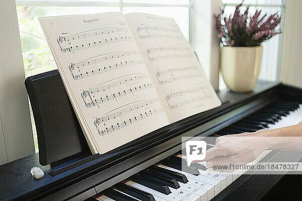Hand of woman playing piano at home
