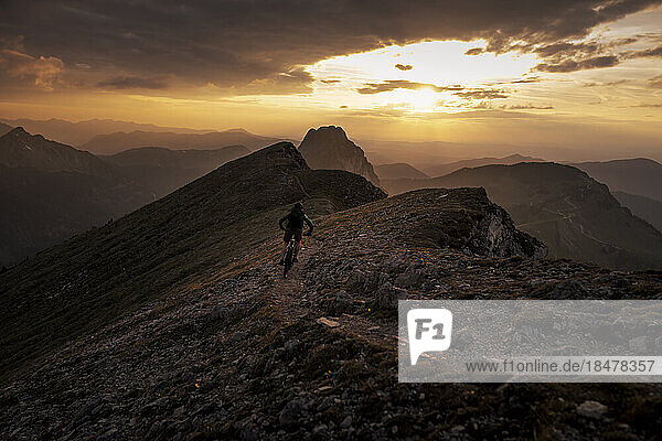 Mann beim Mountainbiken bei Sonnenuntergang