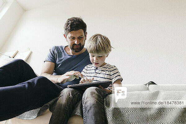 Vater und Sohn sitzen zu Hause mit Tablet-PC