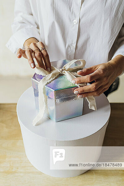 Hands of woman tying ribbon on gift