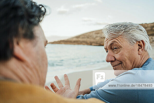 Man having discussion with father sitting on beach