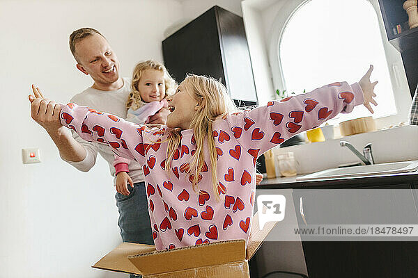 Cheerful daughters enjoying together with father at home
