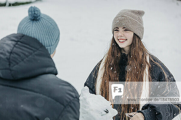 Happy woman looking at boyfriend in snowy park
