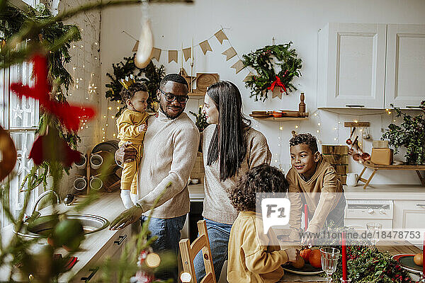 Happy parents spending time with son and daughters in kitchen at Christmas
