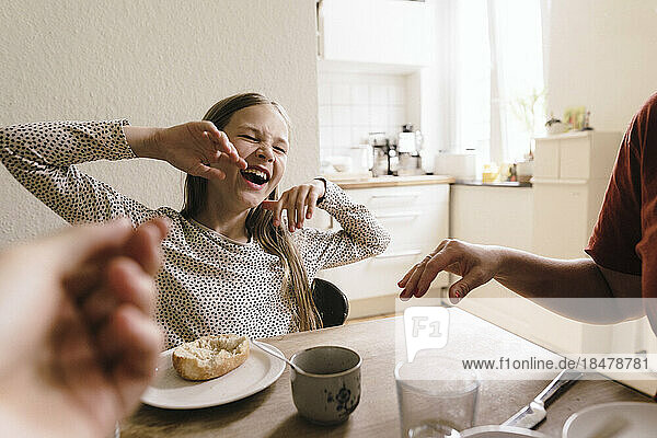 Happy girl laughing with breakfast on table at home
