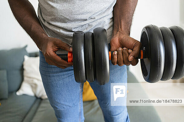 Man exercising with dumbbell at home