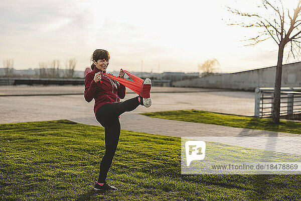 Happy mature woman exercising with resistance band in park