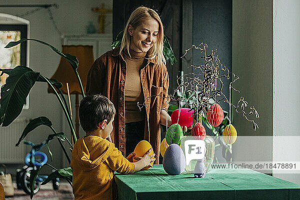 Smiling mother and son decorating table for Easter dinner at home