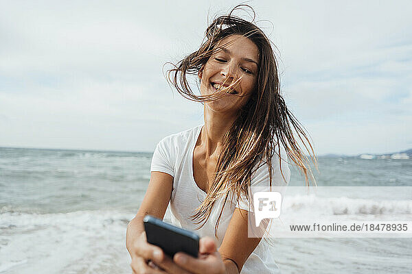 Sorglose Frau benutzt Mobiltelefon am Strand