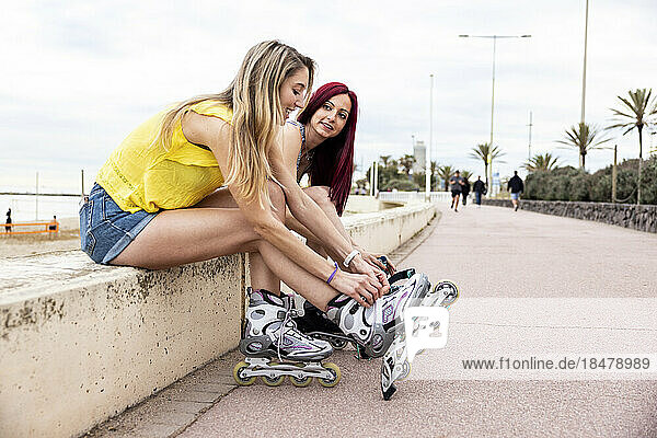 Frauen binden Schnürsenkel von Inline-Skates an der Promenade