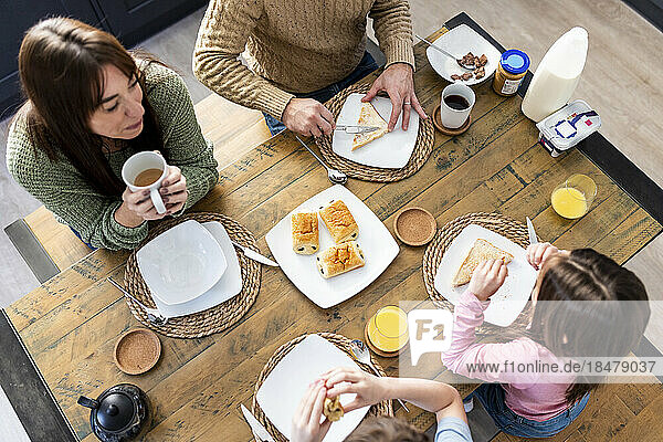 Man and woman having breakfast with children at table