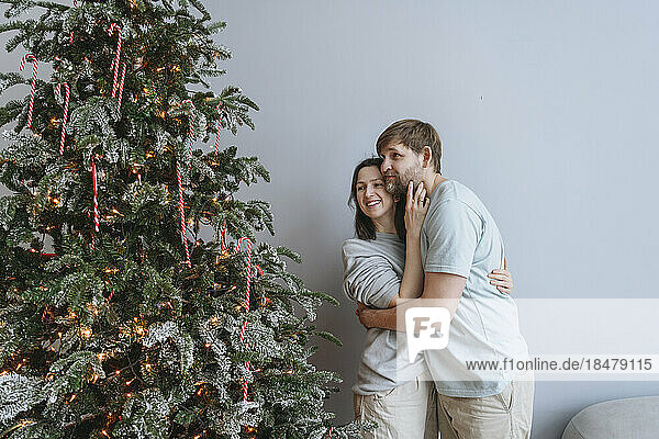 Couple embracing and looking at Christmas tree