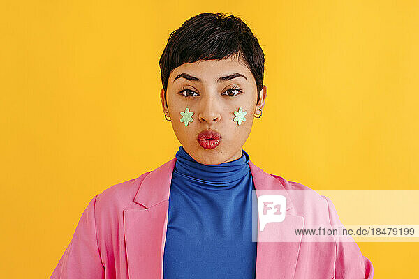 Woman with stickers on face against yellow background