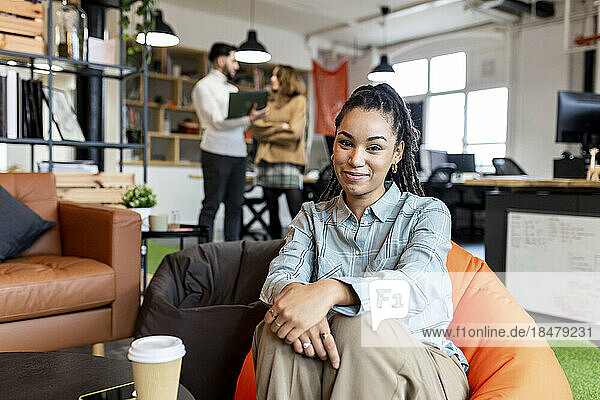 Smiling businesswoman sitting on bean bag in office