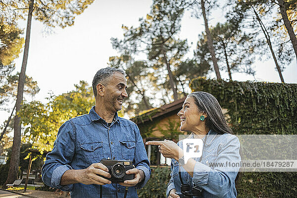 Glückliches reifes Paar mit Kamera und Fernglas im Freien