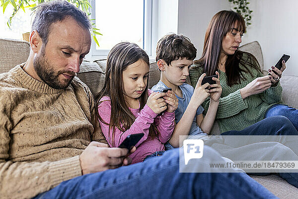 Family using smart phone on sofa at home