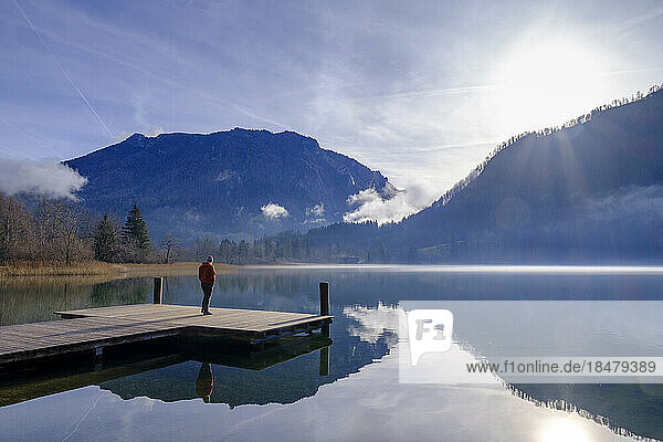 Austria  Lower Austria  Lunz am See  Man admiring sunrise over Lunzer See lake from edge of jetty
