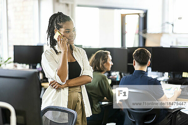 Smiling businesswoman talking on mobile phone in office
