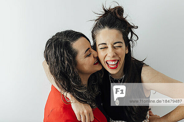 Happy bisexual couple enjoying in front of white wall