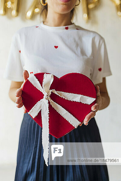 Woman standing with heart shape gift box