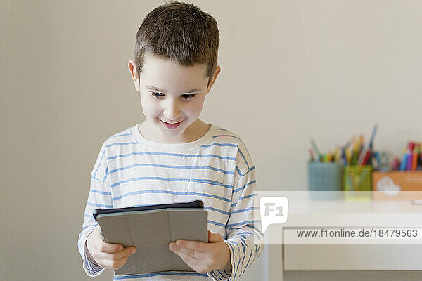 Smiling boy watching tablet PC at home