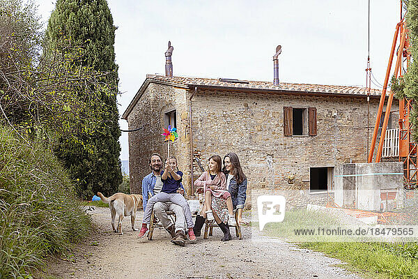 Glückliche Familie mit Hund  der vor dem Haus sitzt
