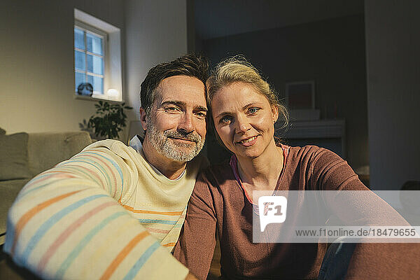 Smiling husband and wife in living room at home