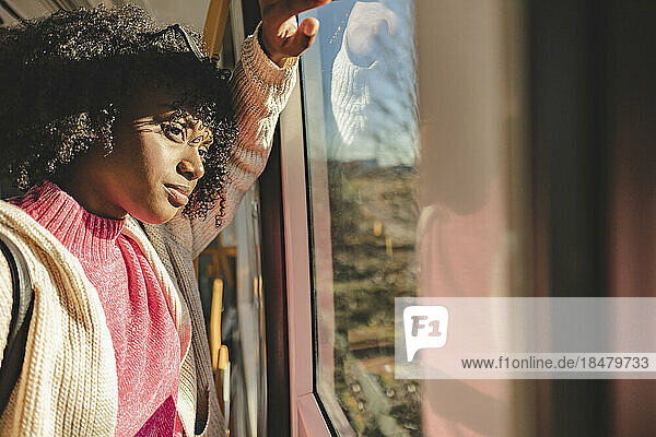 Thoughtful young woman looking through window in tram