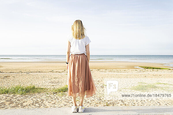 Frau steht an einem sonnigen Tag am Strand